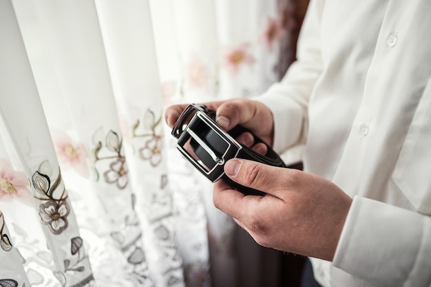 Businessman putting on a belt fashion and clothing conceptgroom getting ready in the morning before ceremony