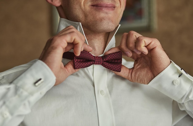 Businessman putting on bow tie man butterfly clothesgroom getting ready in the morning before wedding ceremony