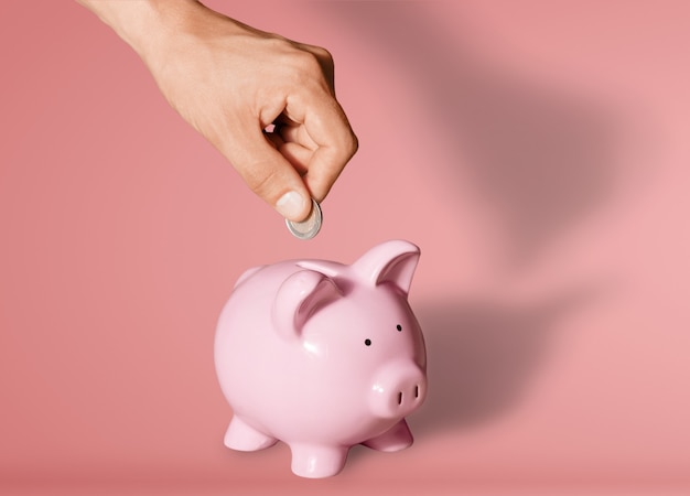 Businessman putting coin into the piggy bank