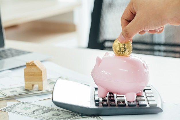 Businessman putting a coin into a pink piggy bank 