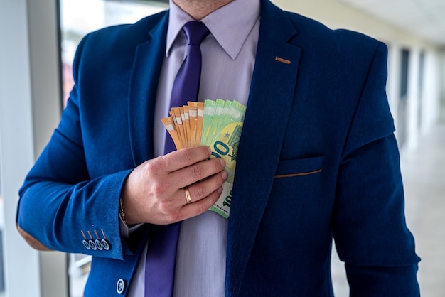 Businessman putting euro money in his pocket, salary or bribe corruption concept