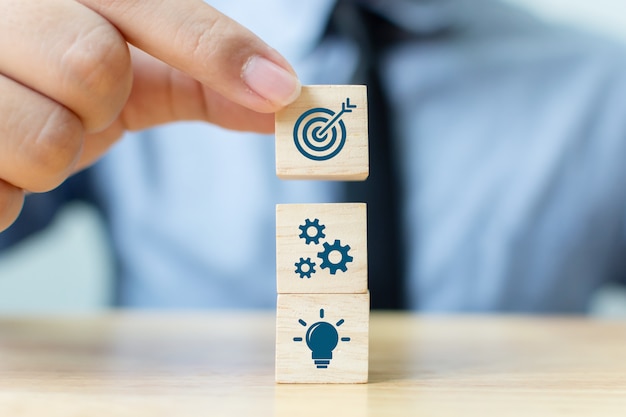 Businessman putting wooden block on top with icons