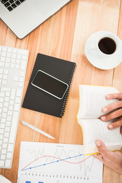 Businessman reading book on wooden desk