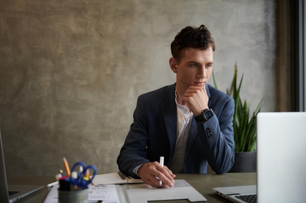 Businessman Reading Documents on Laptop