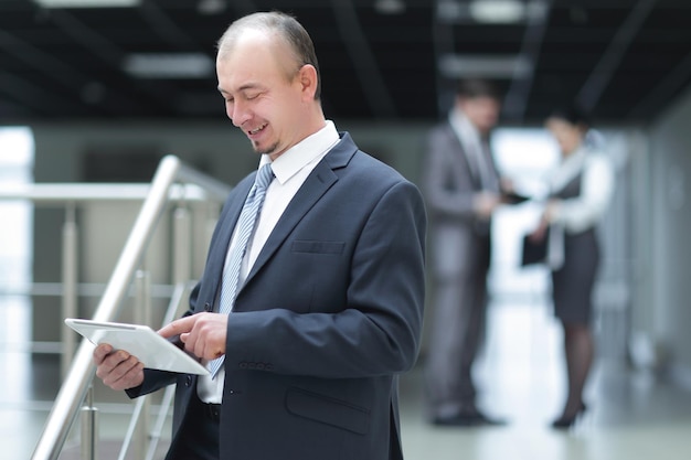 Businessman reading text on a digital tablet standing in office