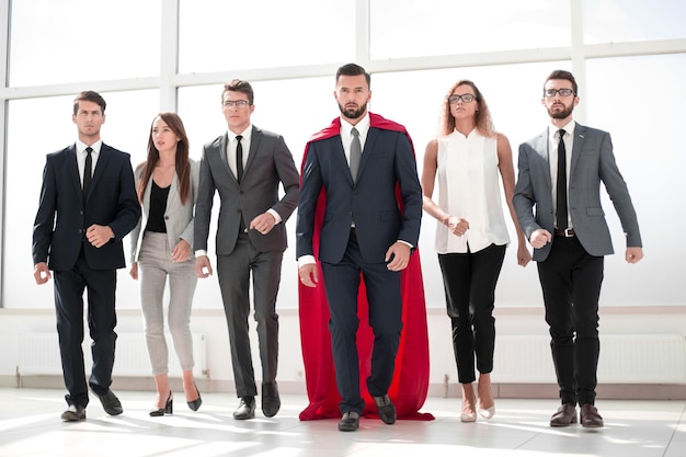 Businessman in a red superhero cloak and his business team