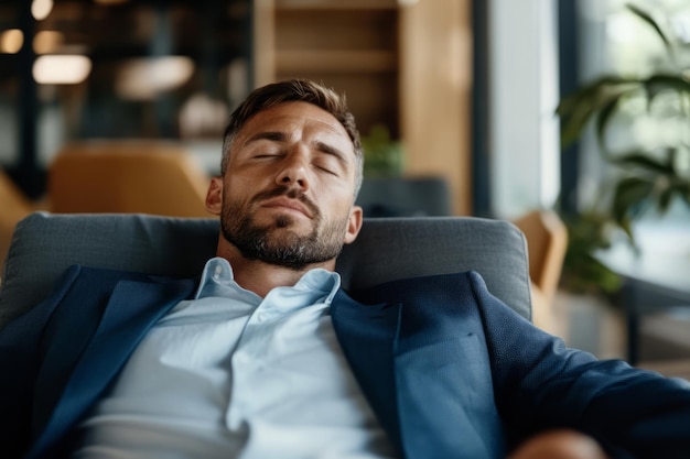 Businessman rests with his eyes closed while sitting in a modern office