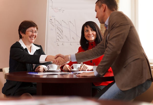 Businessman rising to his feet and shaking hands with a woman executive