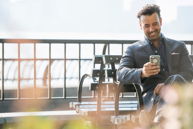 A businessman seated checking his phone laughing