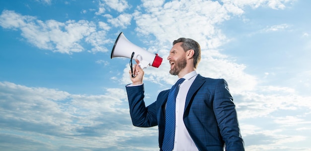 Businessman shout in megaphone on sky background