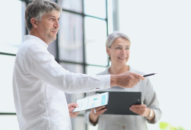 Businessman showing something to mature businesswoman seen throu