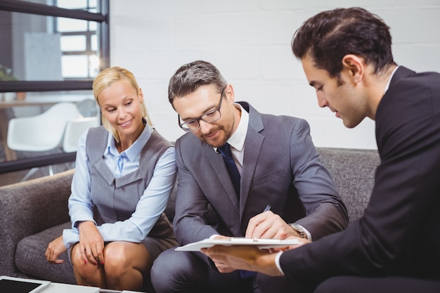 Businessman signing contract while sitting on sofa