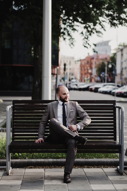 Businessman sitting on bench after work on city street