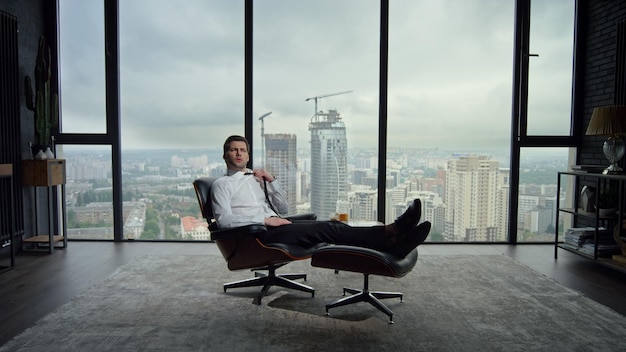 Businessman sitting on chair in modern interior Professional adjusting tie