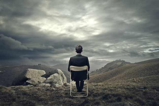 Businessman sitting on a chair on the mountain