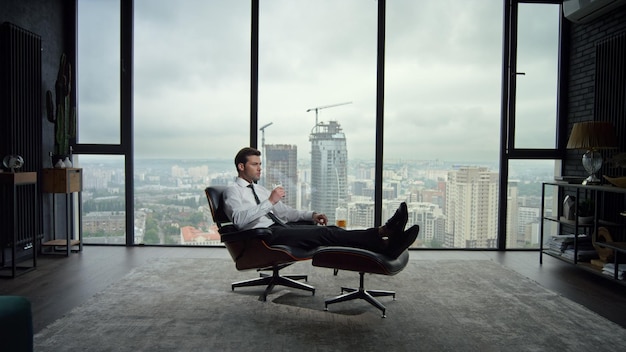 Businessman sitting on chair in office interior Business man drinking scotch