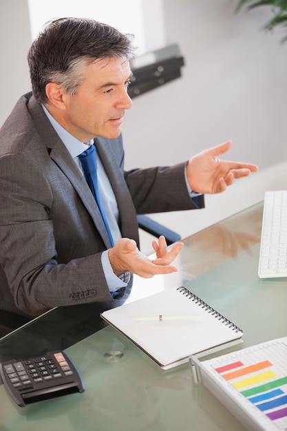 A businessman sitting at his desk explaining something 