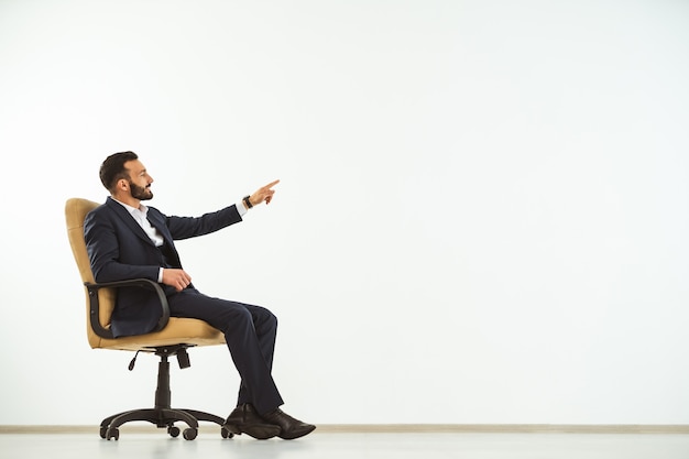 The businessman sitting on an office chair on the white background and gesturing