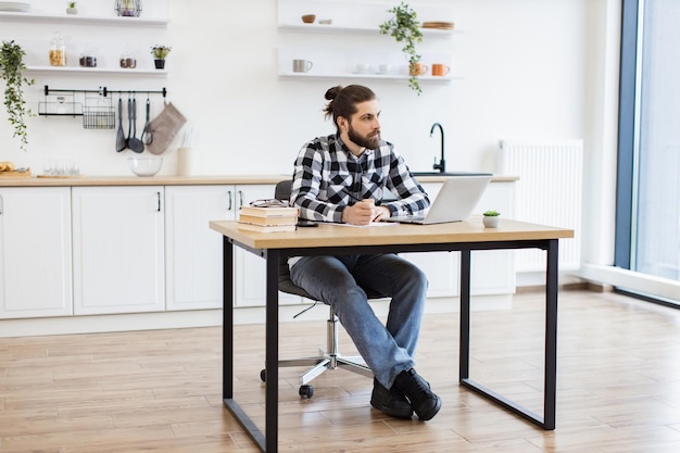 Businessman sitting at office desk with digital devices in spacious dining room