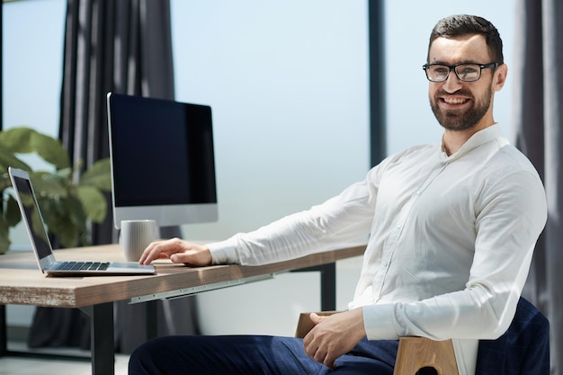 Businessman sitting at office desk working on laptop computer