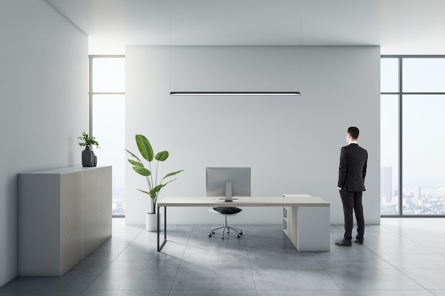 Businessman standing in modern white office interior with furniture and other objects CEO and executive concept