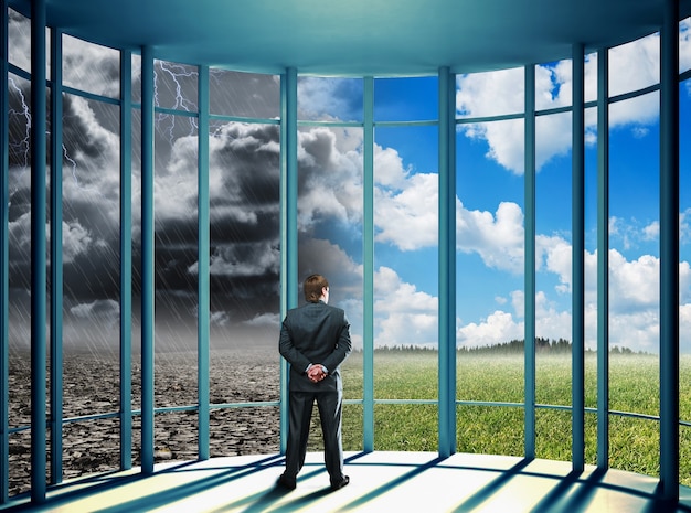 Businessman standing in the office and looking at changeable nature