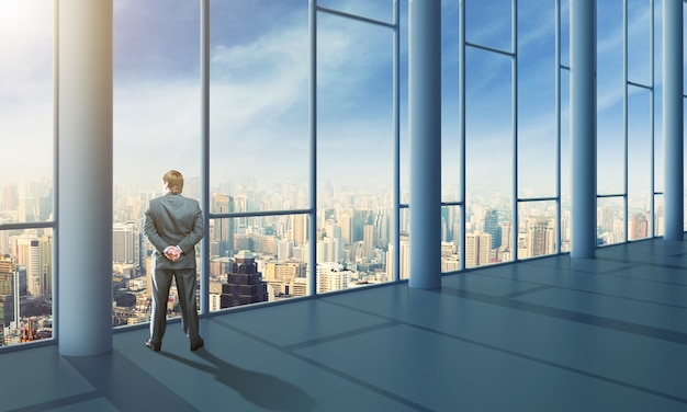 Businessman standing in the office and looking at the sky