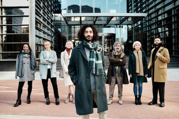 Businessman standing out from a group of business people while posing together against an office building.