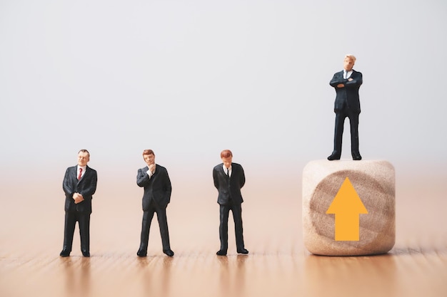 Businessman standing on wooden cube which higher level from three businessmen standing on floor for promotion from staff to management concept