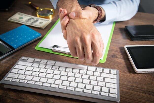 Businessman suffering from hand pain in office