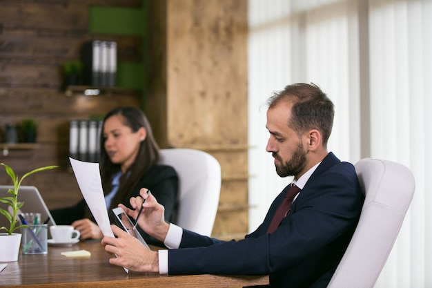 Businessman in suit in a conference room working on tablet. Leadership meeting.