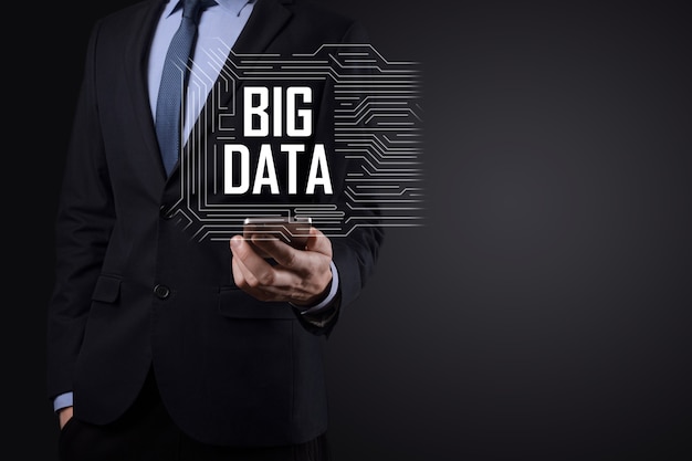 Businessman in a suit on a dark background holds the inscription BIG DATA. Storage Network Online Server Concept.Social network or business analytics representation