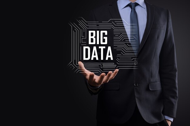 Businessman in a suit on a dark background holds the inscription BIG DATA. Storage Network Online Server Concept.Social network or business analytics representation