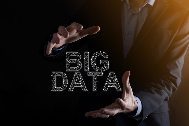 Businessman in a suit on a dark background holds the inscription BIG DATA Storage Network Online Server ConceptSocial network or business analytics representation