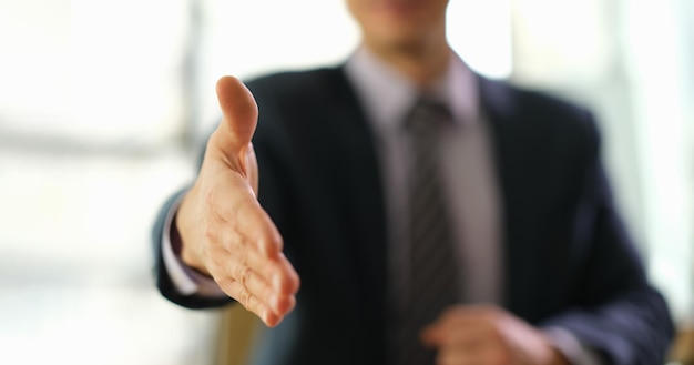 Businessman in suit extending his hand to partner for handshake closeup