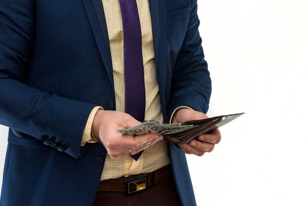 Businessman in suit gets us money from the wallet, isolated. Male hands holding a black leather wallet with US Dollars cash inside. Business, finances and money concept