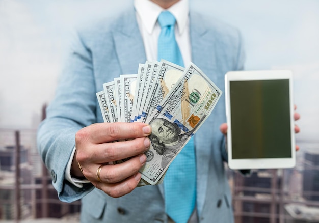 Businessman in suit hold dollar and tablet at office online purchase concept