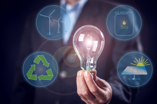 Businessman in suit holding in hands bulb with virtual sign of alternative energy. People and environmental protection concept