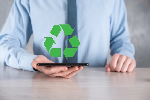 Businessman in suit holds an recycling icon sign in his hands