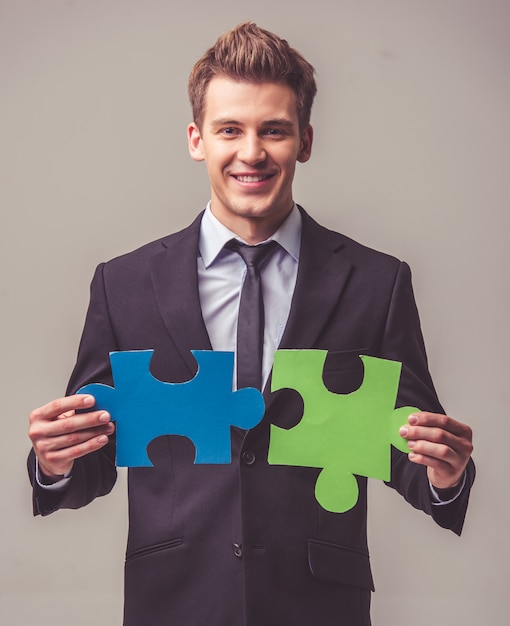 Businessman in suit is holding pieces of puzzle