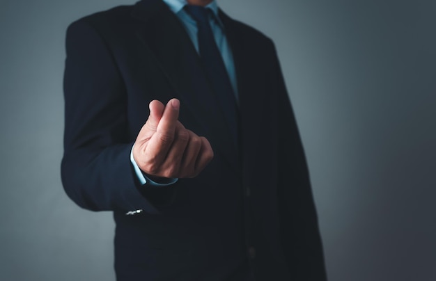 Businessman in suit making mini heart hand gesture on grey background