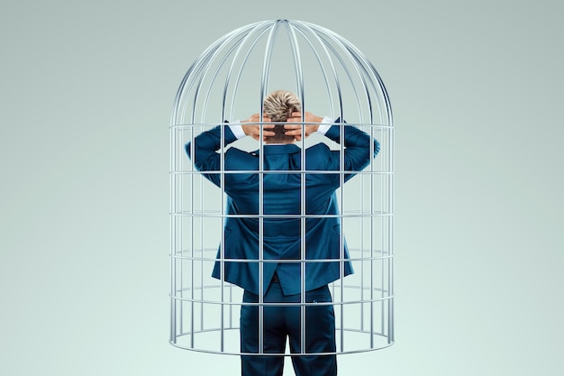 Businessman in a suit in a metal cage Possibilities are limited business metaphor mind prison problems difficulties