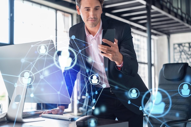 Businessman in suit using smart phone to check new candidates for international business consulting HR social media icons over modern panoramic office background