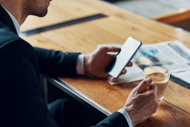 businessman in suit using smart phone and holding cup with coffee