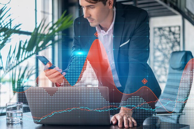 Businessman in suit using smart phone to optimize trading strategy at corporate finance fund Forex chart hologram over modern panoramic office background