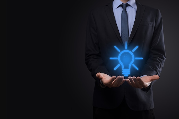 Businessman in a suit with a light bulb in his hands. Holds a glowing idea icon in his hand