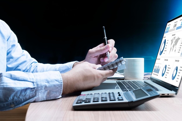 Businessman take note to notebook and laptop with mockup chart presentation slide show on display