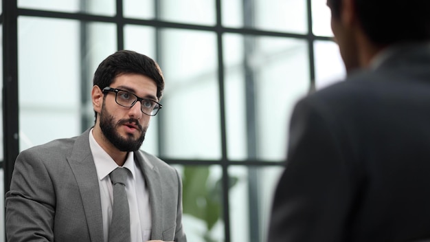 Businessman takes a partner in his office sitting at the table