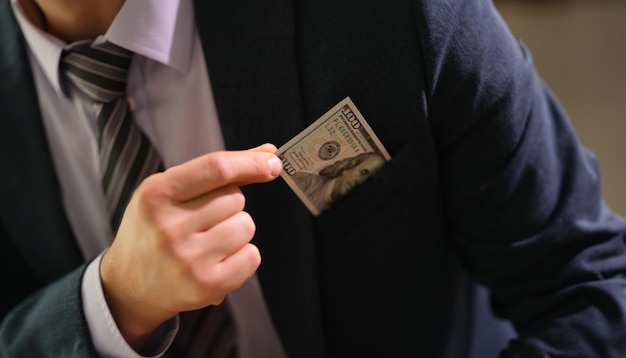 Businessman taking dollar bill out of jacket pocket closeup