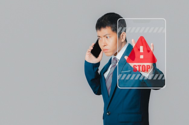 Businessman talking by smartphone and show stop gesture sign by hand with stop sign virtual screen